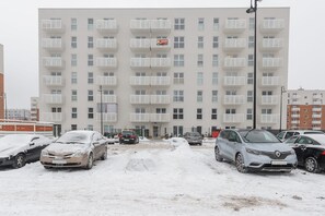 Ein mehrstöckiges Wohngebäude mit Balkonen, ein Parkplatz mit mehreren Autos und ein Schild.