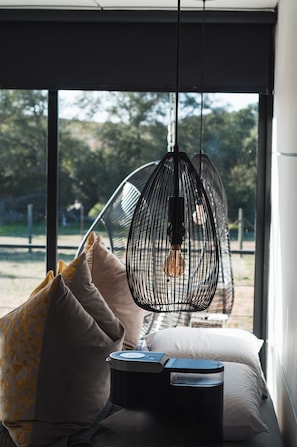 A modern interior with a hanging light fixture, a bed with pillows, and a window with a view of trees. - Villa Boutique(+12) Alberca privada Valle de Gpe (San antonio de las minas)