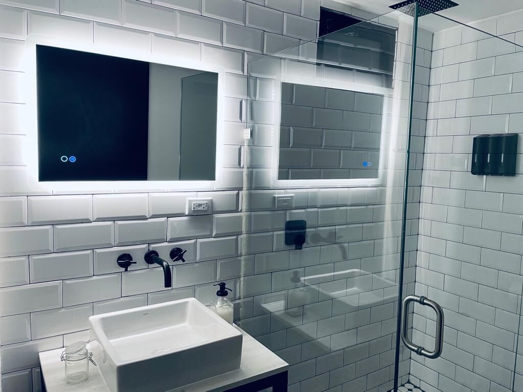 Une salle de bain moderne avec une douche à parois de verre, un lavabo blanc et un miroir au-dessus.