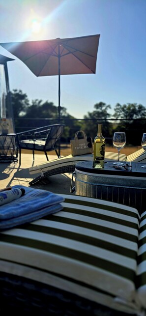 A sunlit outdoor seating area with a table, chairs, and a bottle of wine. - Villa Boutique(+12) Alberca privada Valle de Gpe (San antonio de las minas)