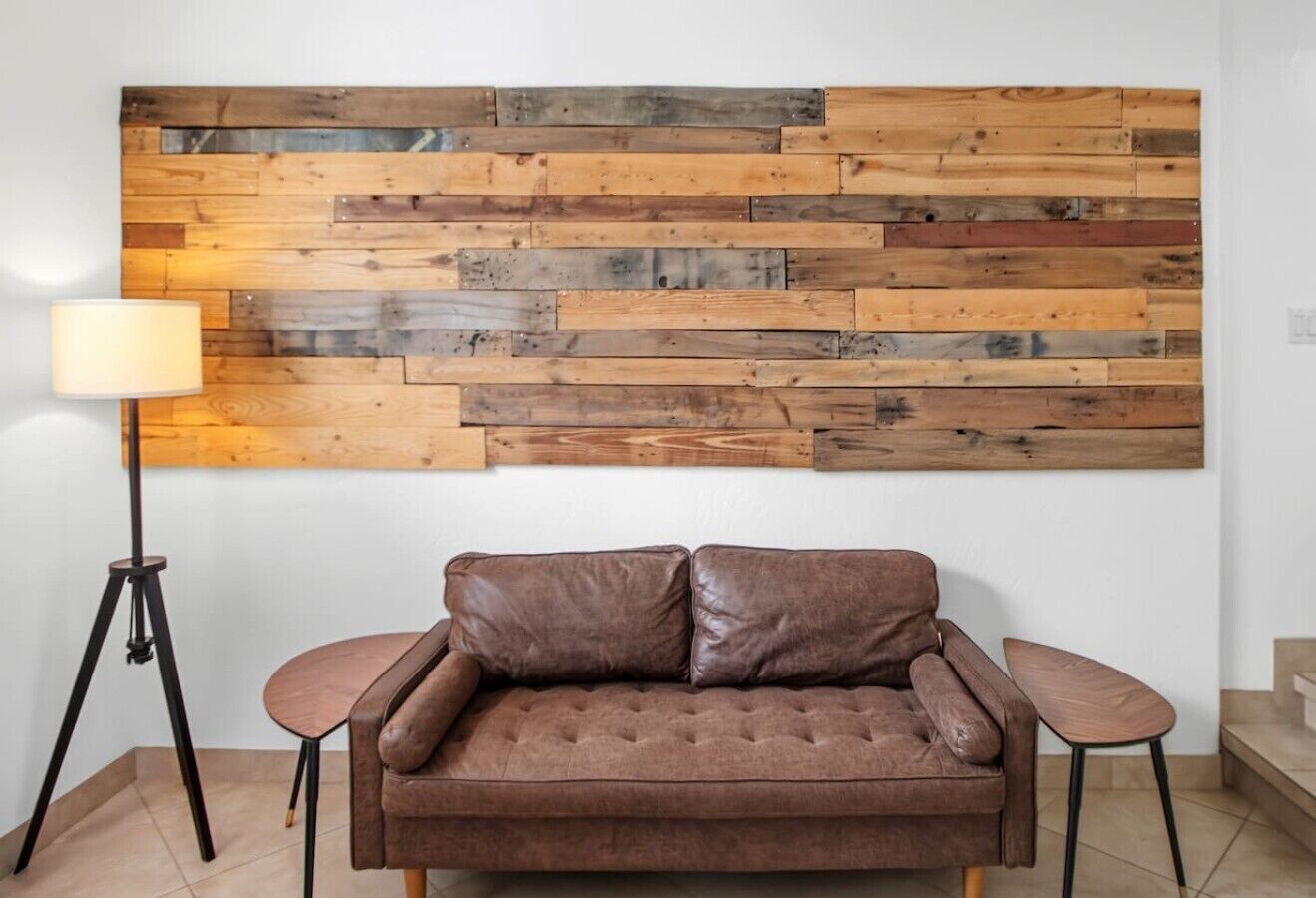 A brown leather sofa with a wooden plank wall behind it.