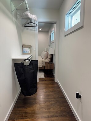 A hallway with a wooden floor, a white wall, a window, and a door leading to a bedroom. - Modern 4BR/3BA Retreat Near East Lake & Downtown Decatur (decatur)
