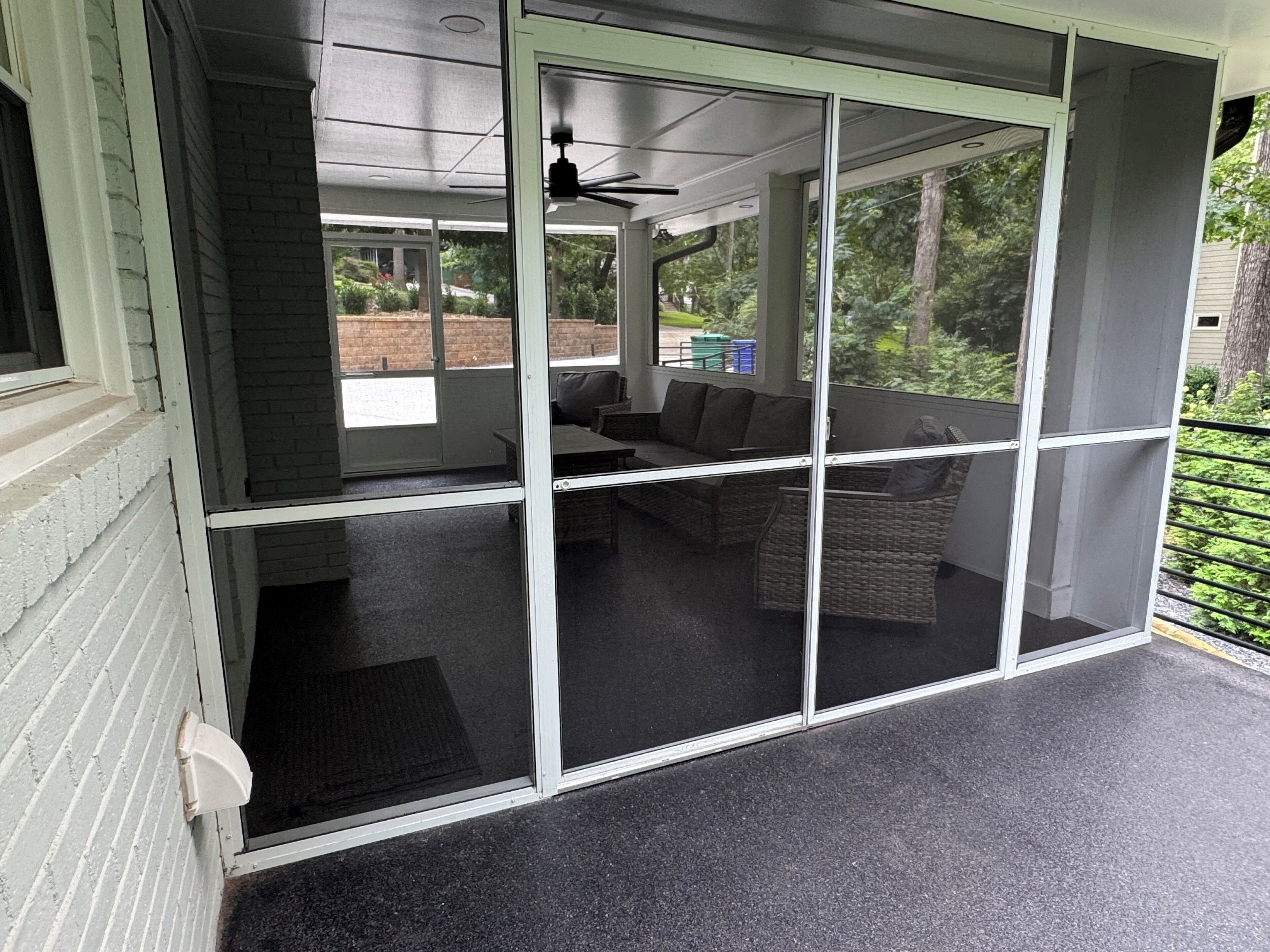 A covered outdoor seating area with a ceiling fan, a sofa, and a table.
