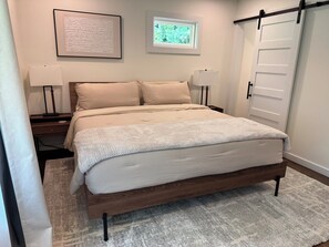A bedroom with a bed, two bedside tables with lamps, a window, and a door. - Modern 4BR/3BA Retreat Near East Lake & Downtown Decatur (decatur)