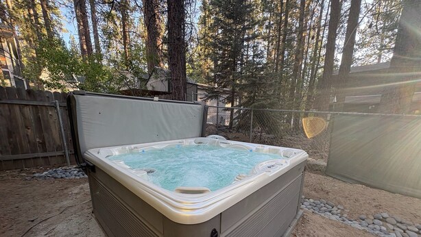 A hot tub in a backyard with a wooden fence and trees in the background. - Alpine Retreat -Hot Tub • Walk to Village, Lake (Big Bear Lake)