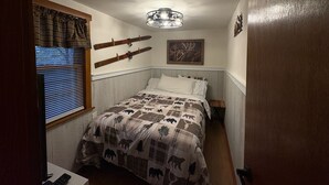A bedroom with a bed, a window with blinds, a wall-mounted light fixture, and a framed picture. - Alpine Retreat -Hot Tub • Walk to Village, Lake (Big Bear Lake)