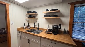 A compact kitchen with a wooden countertop, a sink, and built-in shelves above. - Alpine Retreat -Hot Tub • Walk to Village, Lake (Big Bear Lake)