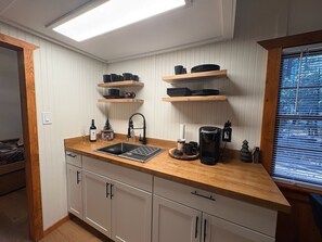 Een compacte keuken met een houten aanrecht, een spoelbak en inbouwplanken erboven.