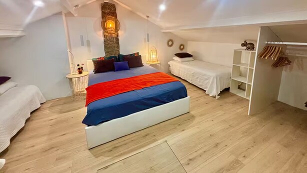 A bedroom with a large bed, a small bedside table, a wardrobe, and a stone wall with a light fixture. - 3-minute walk to the beach, private villa, garden, parking, tram (Nice)
