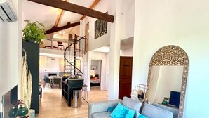 A spacious living area with a large sofa, a coffee table, and a decorative mirror. A spiral staircase is visible in the background, leading to an upper level. - 3-minute walk to the beach, private villa, garden, parking, tram (Nice)
