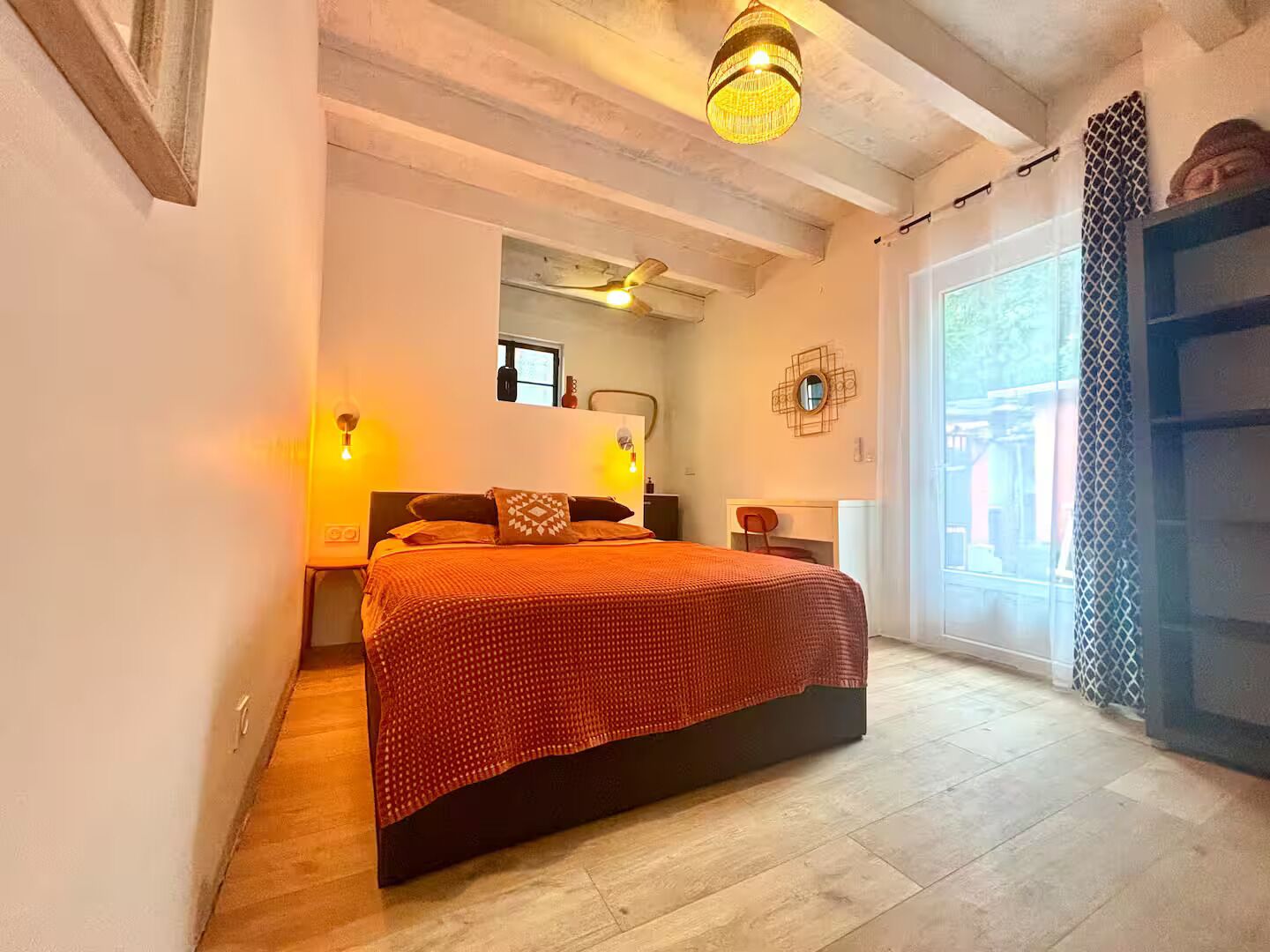 A bedroom with a bed, bedside tables, a mirror, and a window.