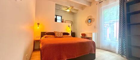 A bedroom with a bed, bedside tables, a mirror, and a window.