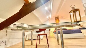 An attic bedroom with a glass ceiling, a wooden beam, a metal table, a red chair, a bed with a blue mattress, and a wall-mounted lantern. - 3-minute walk to the beach, private villa, garden, parking, tram (Nice)