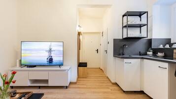 Un appartement moderne doté d’une télévision, d’une kitchenette et d’un couloir menant à une autre pièce.