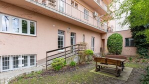 A residential building with a small garden area, a wooden bench, and a staircase leading to an upper floor. - THE UNDERSTORY, OLD TOWN WALK (Bratislavský kraj)
