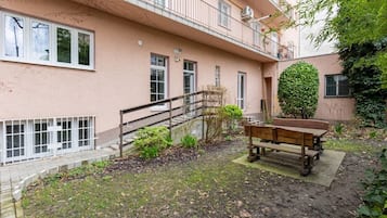 Un immeuble résidentiel doté d’un petit jardin, d’un banc en bois et d’un escalier menant à l’étage supérieur.