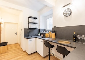 A compact kitchen with a built-in sink, a small bar area, and a clock on the wall.