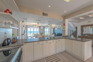 A spacious kitchen with white cabinetry, a granite countertop, and a view to the living area.