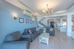A spacious living area with a staircase leading to an upper floor, a dining area, and a kitchen.