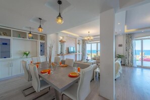 A modern dining area with a large table, chairs, and pendant lighting.