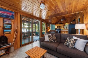L’intérieur d’une cabane est doté d’un plafond en bois, d’un canapé avec des coussins à motifs, d’un coin repas et d’une cuisine équipée d’un réfrigérateur.