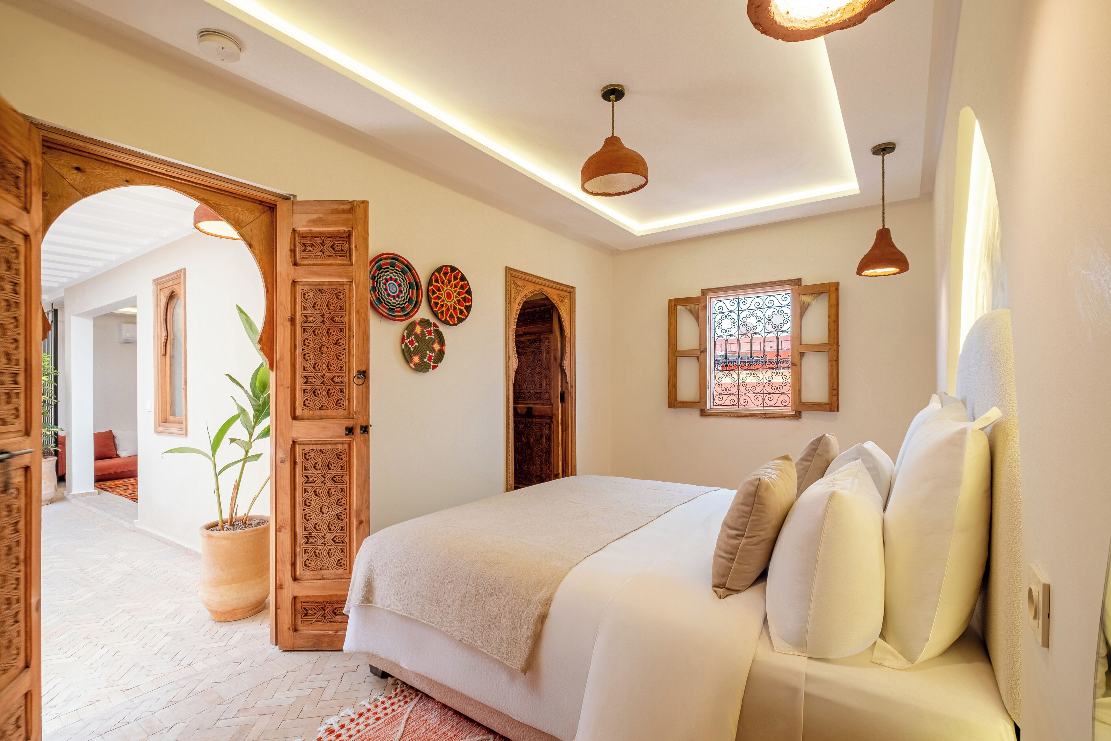 Un dormitorio con una cama grande, puertas de madera y una planta en maceta.