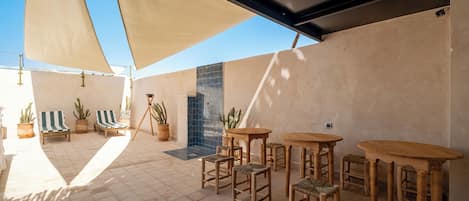 An outdoor patio area with a tiled floor, wooden furniture, and potted plants.