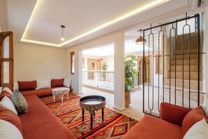 A spacious living room with a sofa set, a patterned coffee table, and a view of the outdoor balcony. - Spacious 6-bedroom riad in charming Marrakesh with A/C (Marrakesh)