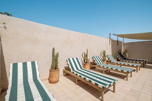 A rooftop lounge area with striped lounge chairs and potted cacti. - Spacious 6-bedroom riad in charming Marrakesh with A/C (Marrakesh)
