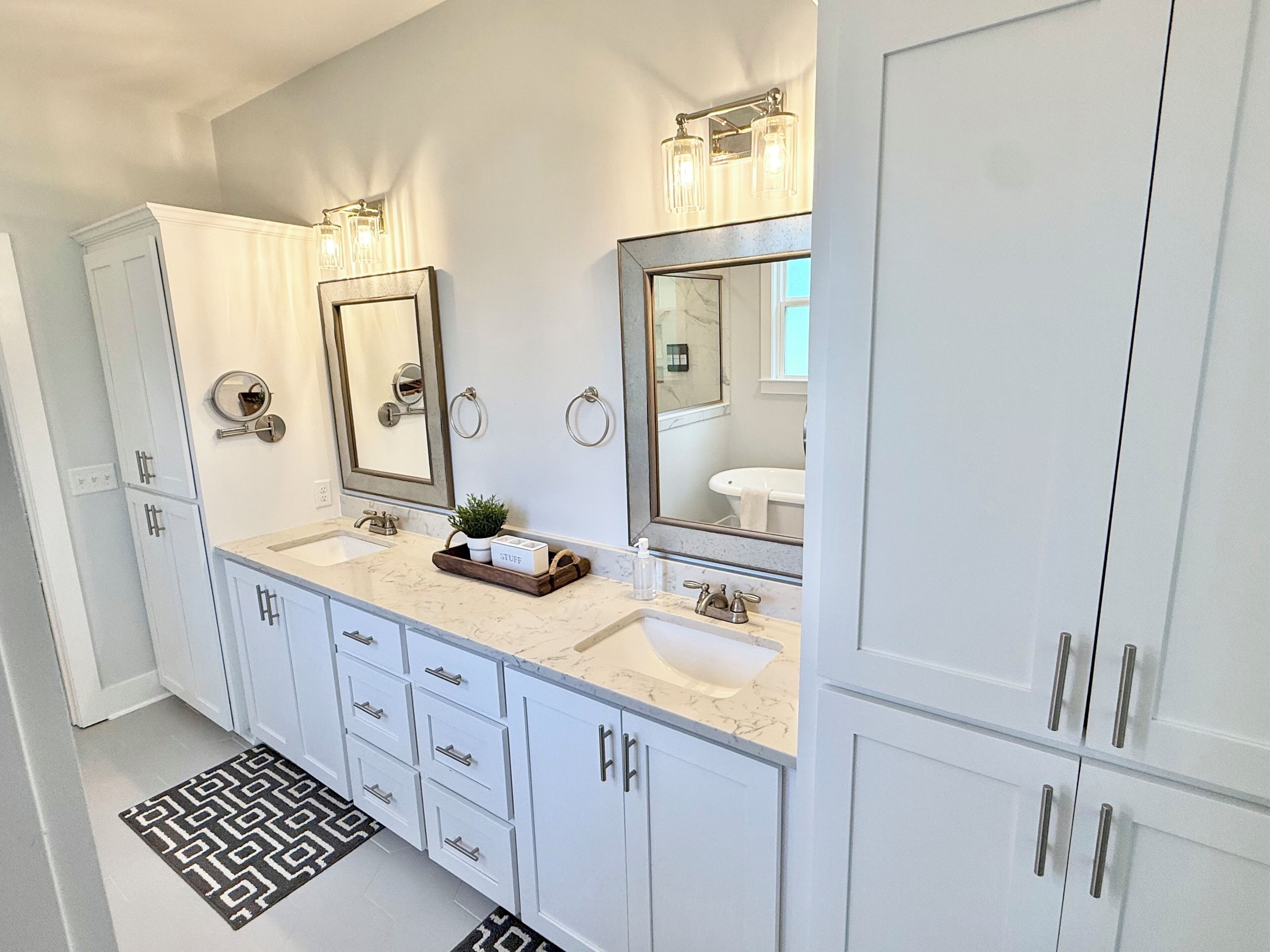 A modern bathroom with two sinks, a large mirror, and a vanity with drawers.