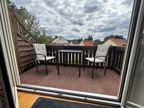 Une terrasse avec deux chaises et une table, entourée d’une rambarde en bois.