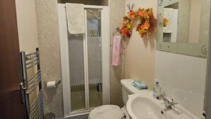 A bathroom with a toilet, sink, shower, and a mirror with a decorative frame. - RM4 - Perfect 1-bedroom, Shower inside room with free onsite parking. (Aberdeen)