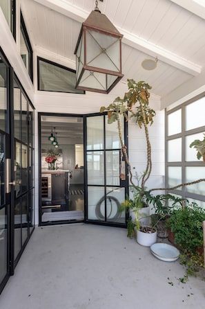 A modern interior with a glass door entrance, a hanging lantern, and potted plants. - Beach House/Rare Rooftop Deck/9 Homes from sand/few blocks to Down Town (Manhattan Beach)