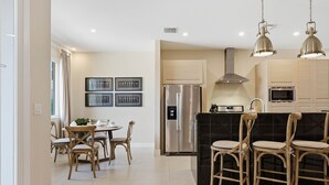 Uma cozinha moderna com uma ilha central, eletrodomésticos de aço inoxidável e uma área de jantar com cadeiras de vime.