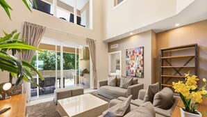 Uma sala de estar espaçosa com um amplo sofá, uma mesa de centro e uma área de jantar com mesa de madeira.