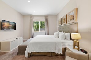 A bedroom with a bed, a bedside table with a lamp, a TV mounted on the wall, and a window with curtains. - Stylish 4 Ensuite Home Near Disney, free BBQ grill (Kissimmee)