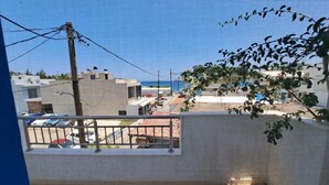 Vista de uma varanda com vista para a costa, prédios, céu claro e o mar ao longe.
