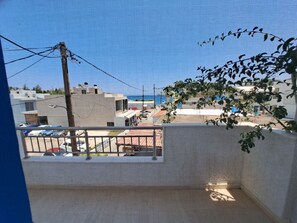 A view from a balcony overlooking a coastal area with buildings, a clear sky, and a distant view of the sea. - Marvelous 1-bedroom apartment with AC in Αγια Πελαγια (ΑΓΙΑ ΠΕΛΑΓΙΑ)