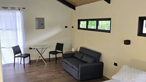 Een hotelkamer met een bed, een bank, een eettafel met stoelen en een raam.