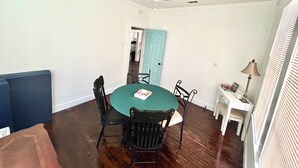 Comedor con una mesa redonda, cuatro sillas, un ventilador de techo y una puerta que da a otra habitación.