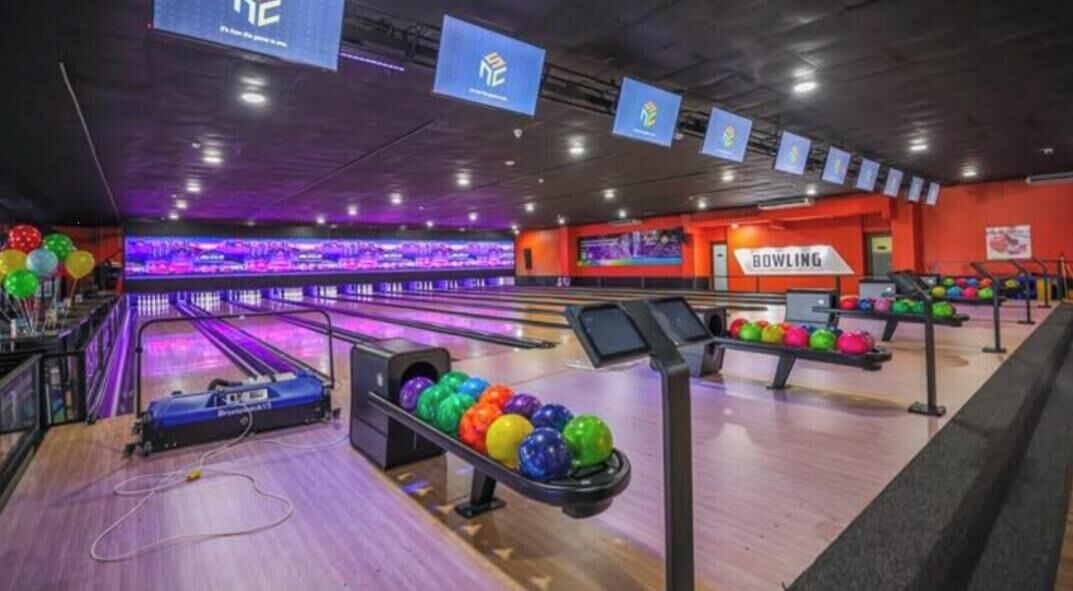 Bolera amb diverses pistes, un sistema de retorn de pilotes i un rètol que diu 'BOWLING'.