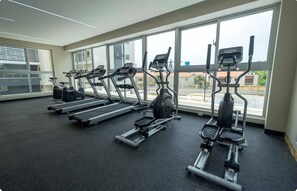 A gym with treadmills, ellipticals, and a stationary bike, large windows, and a black rubber floor. - Excentric at Juan Dolio Beach (Juan Dolio)