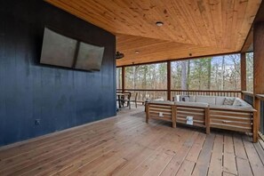 Una terraza de madera con un banco integrado y un televisor montado en la pared.