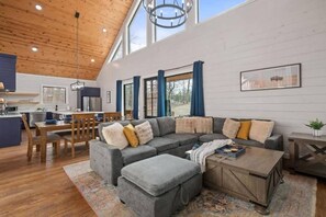 A spacious living area with a large gray sectional sofa, a wooden coffee table, and a dining area with a wooden table and chairs. - Hot Tub, Fire Pit, Ping Pong, Near Beavers Bend (Broken Bow)