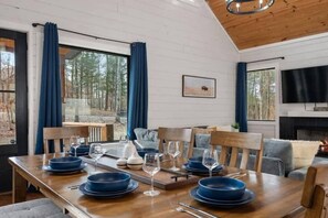 A dining area with a wooden table set for four, blue plates, and glasses. - Hot Tub, Fire Pit, Ping Pong, Near Beavers Bend (Broken Bow)