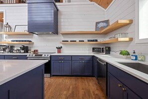 Una cocina moderna con armarios azul oscuro, una encimera blanca y un techo de madera.
