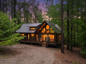 Eine Holzhütte mit Veranda, einer Holzdiele und einem Schotterweg.