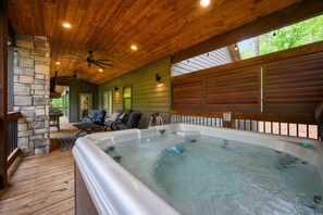 Ein Whirlpoolbereich mit Steinwand, Holzboden und einer Sitzecke mit Sesseln.
