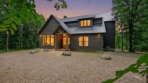 Ein zweigeschossiges Haus mit Schotterauffahrt, Holzveranda und Metalldach.
