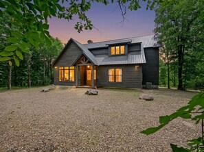 Ein zweigeschossiges Haus mit Schotterauffahrt, Holzveranda und Metalldach.